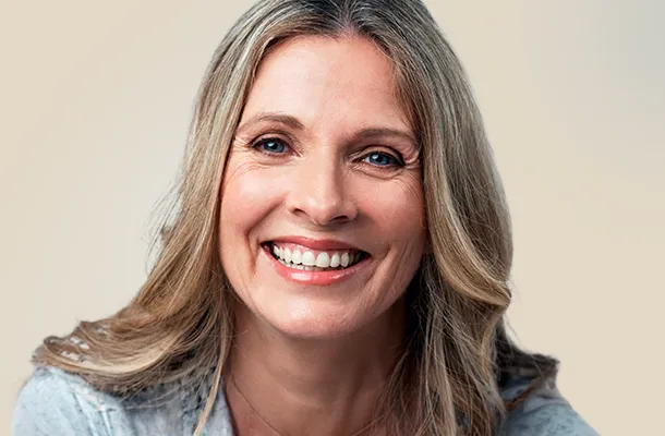 Vrouw van middelbare leeftijd met een stralende glimlach en gezonde huid – esthetische behandelingen voor een natuurlijk resultaat