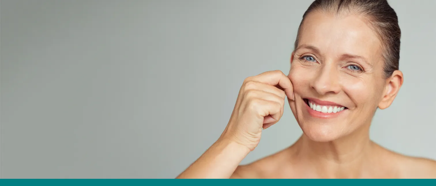 Een vrouw met rijpe huid test de elasticiteit van de huid van haar gezicht.