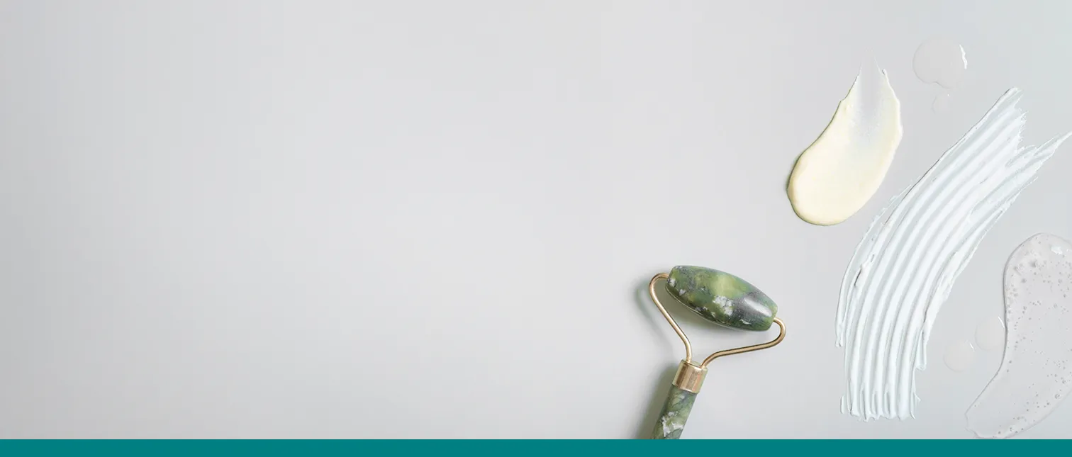 Huidcrèmes en lotions met verschillende texturen, en een gua sha-roller.