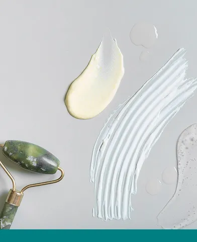 Huidcrèmes en lotions met verschillende texturen, en een gua sha-roller.