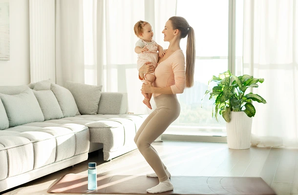 Een jonge vrouw staat op een yogamat met een baby in haar armen